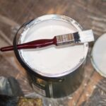 Redecorating - red handle paint brush in white paint bucket