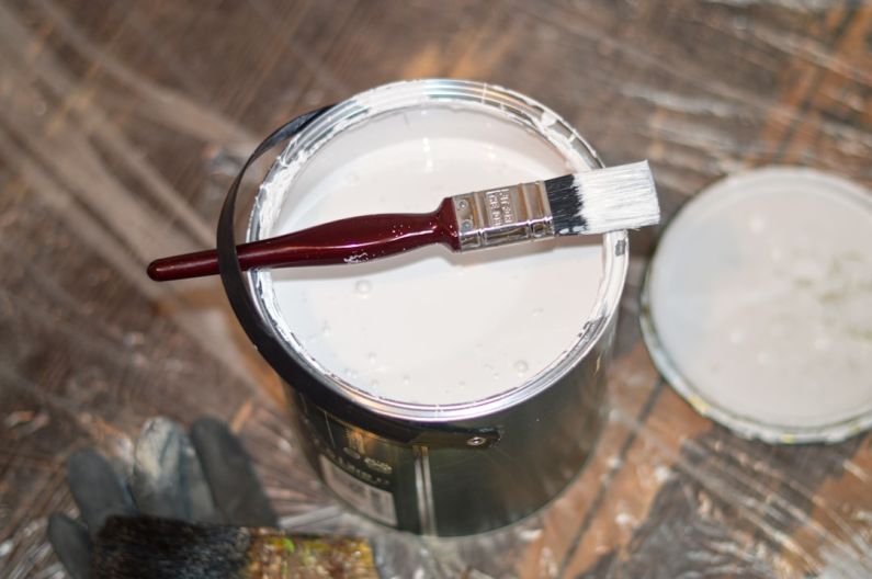Redecorating - red handle paint brush in white paint bucket