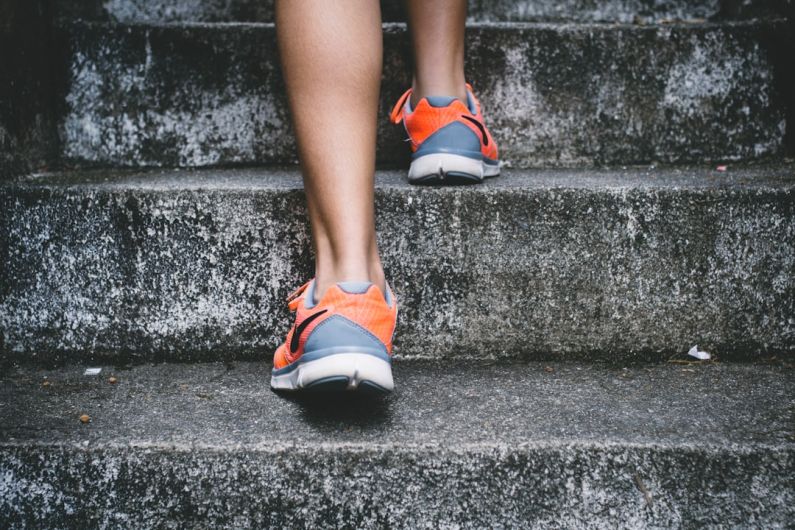 Outdoor Fit - person wearing orange and gray Nike shoes walking on gray concrete stairs
