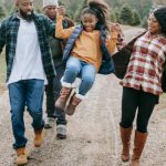 Raise Kids - Ethnic parents raising cheerful girl on tree farm roadway