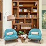 Living room with cozy chairs near lamp and wooden bookcase