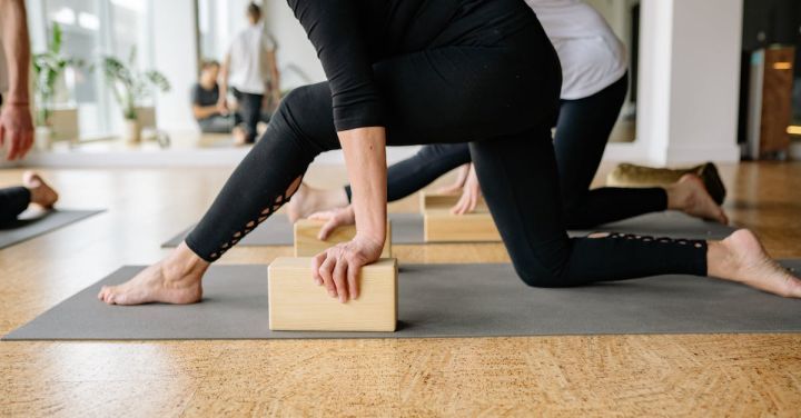 Fitness Classes - Woman in Black Leggings and Black Long Sleeve Shirt Sitting on Brown Wooden Floor