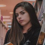 School Shopping - Woman in Black Top Leaning by Bookcase