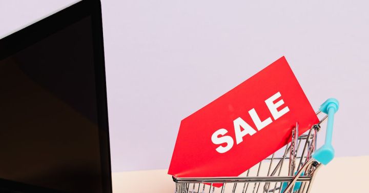 Electronics Discounts - A Red Sale Tag on a Miniature Shopping Cart Placed on a Macbook Laptop
