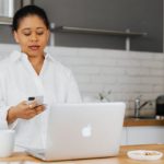 Kitchen Gadgets - Woman in Button-Up Shirt Using a Cellphone